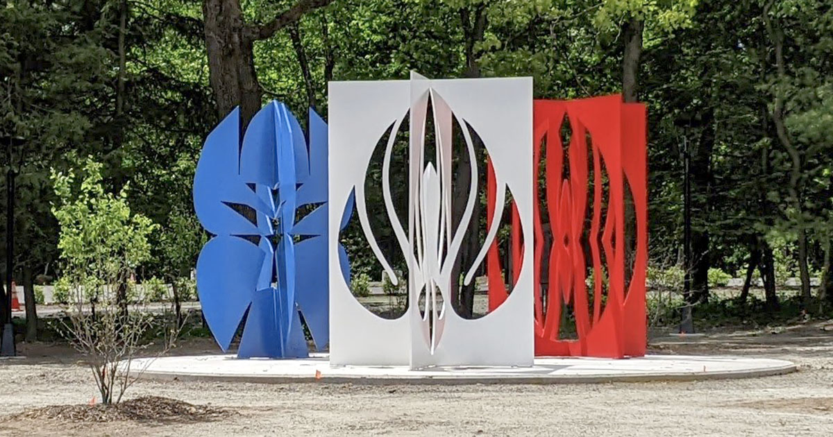 three large metal sculptures in blue white and red that look like paper cut outs