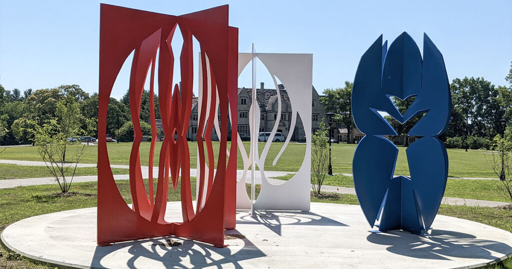 three large metal sculptures in blue white and red that look like paper cut outs