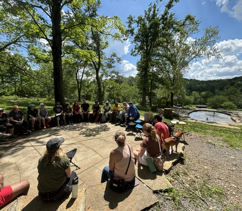 Group of park visitors sitting in a circle at the Cascades on a beautiful spring day.